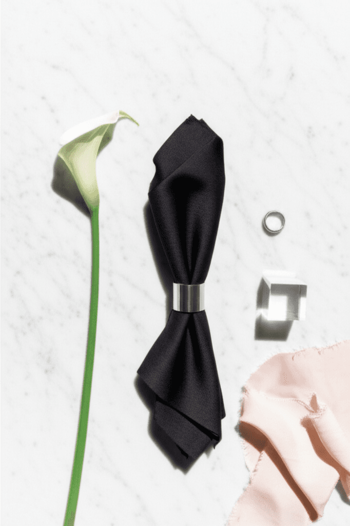 Modern minimalist wedding flatlay with monochrome elements on white marble