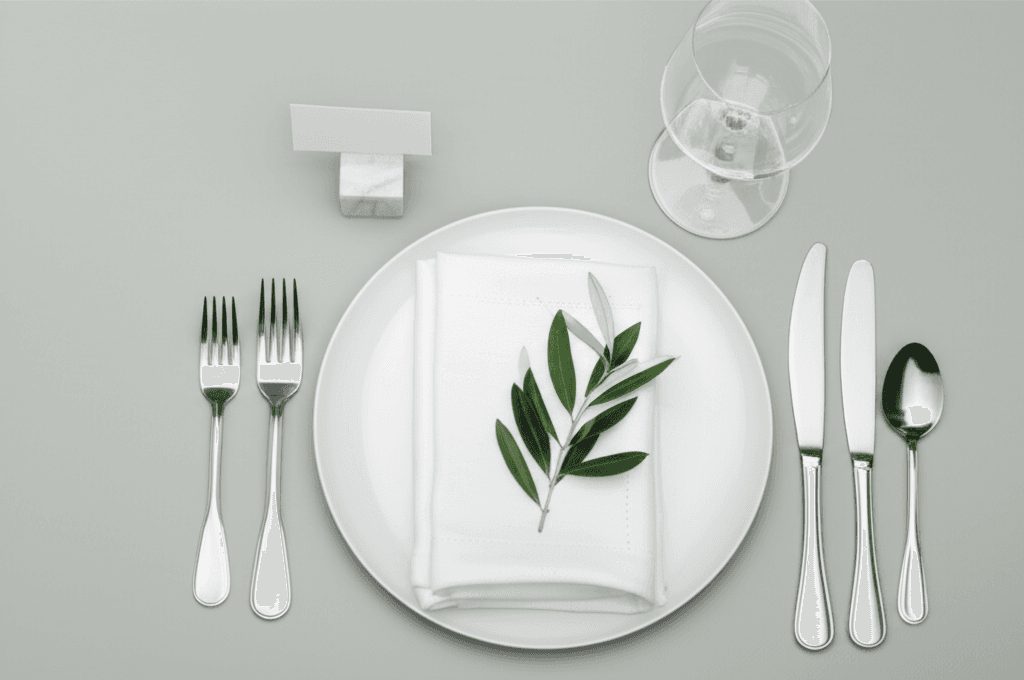 Impeccable modern minimalist wedding place setting with flat-rimmed plates and brushed silver flatware